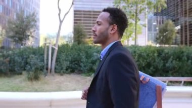 Yakışıklı Afro-Amerikan iş adamının şehir caddesinde yürüyüşünün yan görüntüsü.