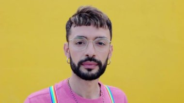Sarı arka planda kameraya bakan neşeli sakallı eşcinsel adamın gülümseyen portresi. LGTBQ insanları kavramı