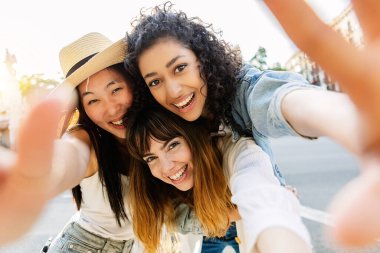 Üç çok ırklı genç kadın şehir sokaklarında eğleniyor. Milenyum arkadaş grubu yaz tatilinin tadını çıkarıyor açık havada selfie çekiyorlar. Arkadaşlık ve gençlik kavramı.