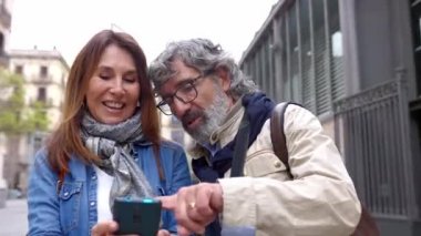 Dışarıda cep telefonu kullanan orta yaşlı bir aile çifti. Olgun erkek ve kadın akıllı telefon ekranına bakarken tartışıyorlar. Teknoloji yaşam tarzı konsepti