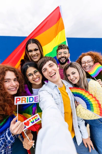 LGBTQ topluluğundaki insanlar eşcinseller günü festivalini telefonla dikey selfie çekerek kutluyorlar. Genç homoseksüel erkek ve kadınlar birlikte dışarıda eğleniyorlar. LGBTQI konsepti.
