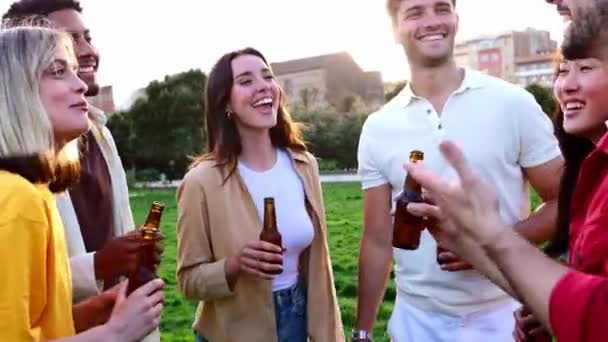 一緒に外のビールボトルで応援を祝う若い友人のグループ 夏のパーティーを屋外で楽しんで笑っている多人種の幸せな人々 コミュニティ 友情の概念 — ストック動画