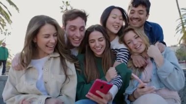 Genç Asyalı kadın arkadaşlarına komik sosyal medya içeriği gösteriyor. Öğrenci milenyum insanları akıllı telefon dijital uygulamasında video izlerken eğleniyor. Teknoloji yaşam tarzı