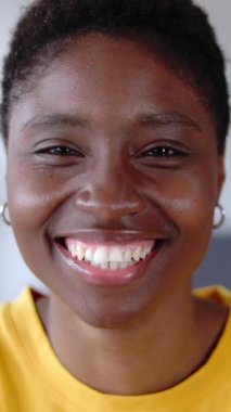 Genç, neşeli, Afro-Amerikan kadın portresi. Evdeki video görüşmesinde kameraya gülümsüyor. Mutlu insanlar konsepti. Dikey video