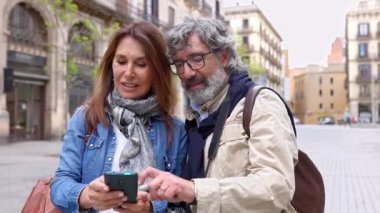 Yaşlı evli bir çift cep telefonunda GPS uygulaması rehberi kullanarak şehri keşfe çıkıyor. Aktif kıdemli aile akıllı telefon haritası uygulamasında yönünü kontrol ediyor. 