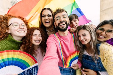 Gökkuşağı bayraklı bir grup genç arkadaş eşcinseller günü festivalini kutluyorlar. LGBT topluluk kavramı.