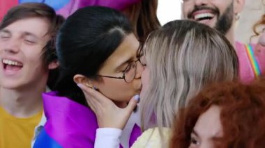Eşcinsel Onur Festivali 'ni kutlayan genç ve çeşitli insanlar grubu. Lezbiyen çift öpüşüyor. Etrafı arkadaşlarla çevrili. LGBT gençlik toplumu kavramı.
