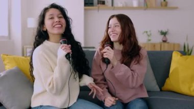 Evde karaoke yapan iki gülümseyen genç oda arkadaşı. Milenyum bayan arkadaşları multimedya ağ oyununda şarkı söyleyerek eğleniyorlar. Ev eğlencesi ve insan konsepti