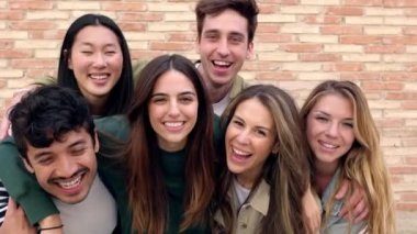 Genç bir grup mutlu insan dışarıda birlikte eğleniyor. Üniversite kampüsünde birleşme ve bütünleşme gösteren çok kültürlü öğrenci arkadaşları bir arada. Gençlik toplumu ve arkadaşlık kavramı.