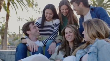 Mutlu bir grup milenyum arkadaşı dışarıda otururken eğleniyor. Çeşitli üniversite öğrencileri birlikte gülüyor ve gülüyor. Sokakta birlikte rahatlıyorlar. Arkadaşlık ve gençlik yaşam tarzı konsepti.