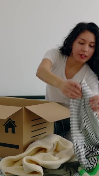 彼女の部屋でベッドに寄付するために段ボール箱の中に服を準備し 置く女性 ボランティア 寄付の考え方 — ストック動画