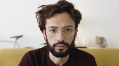 Ciddi bir orta yaşlı sakallı adamın portresi. Evdeki koltukta oturan kameraya bakıyor.. 