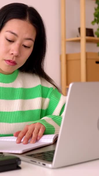 縦スクリーンビデオ 若い笑顔フリーランサー アジアの女性 電卓を使用して自宅でラップトップコンピュータで作業 — ストック動画