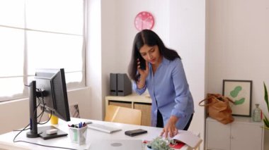Ofiste cep telefonuyla konuşan Hintli profesyonel iş kadını. Başarılı bayan yönetici bilgisayardaki bazı bilgileri kontrol ederken meslektaşını arıyor. İş ve insan kavramı.