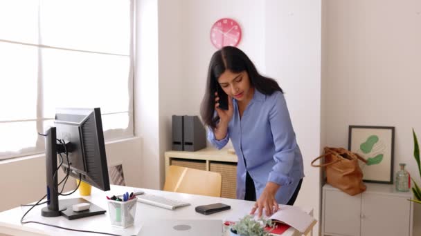 オフィスで携帯電話で話しているプロのインドのビジネスマン 成功した女性マネージャーは コンピュータ上のいくつかの情報をチェックしながら同僚に電話しました ビジネスと人々のコンセプト — ストック動画
