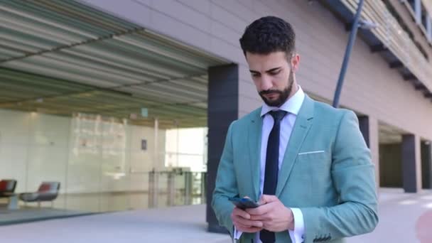 外の建物オフィスに立っている携帯電話を使用して正式なスーツの専門のビジネスマン スマートフォンを持っているスマートフォンの笑顔起業家セールスマン テクノロジーとビジネスコンセプト — ストック動画