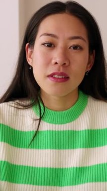 Dizüstü bilgisayardan dinleyen Asyalı genç bir kadının POV ekran görüntüsü. Dikey ekran video.