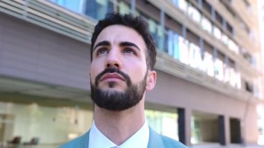 Uzağa bakan profesyonel bir erkeğin yakından çekilmiş portresi bina ofisinin dışından düşünüyor. Düşünceli sakallı iş adamı şehir sokaklarında tefekkür ediyor..
