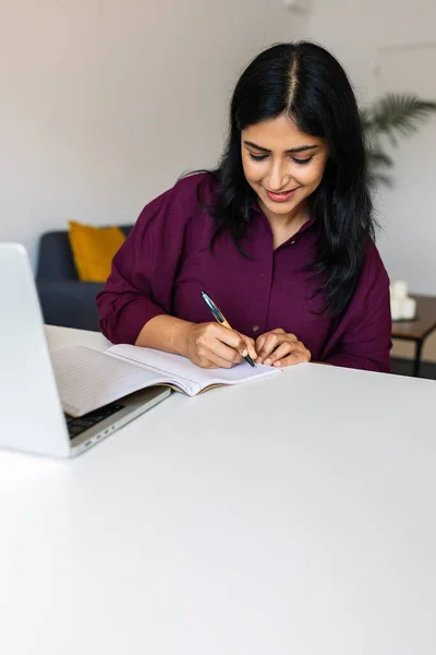 Vertical shot of young adult indian woman studying online from home. Education lifestyle and e-learning.
