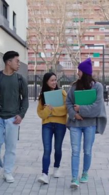 Üniversite kampüsünde yürüyen mutlu Asyalı öğrenciler. Çin halkı ve eğitim kavramı. Dikey görünüm ekran videosu.