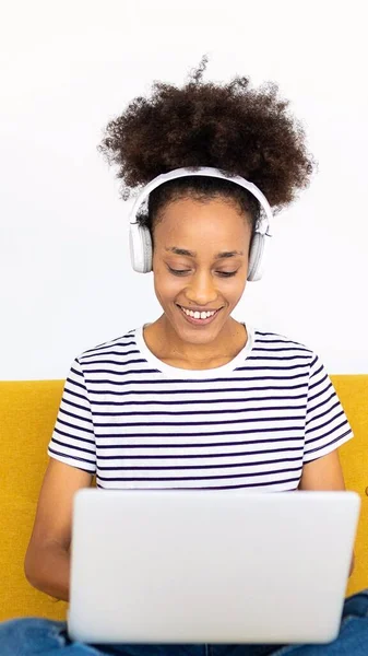 stock image Vertical shot of young woman using laptop sitting on couch at home. Education and e-learning concept.