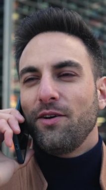 Genç yakışıklı iş adamı dışarıda cep telefonuyla konuşuyor. Başarılı girişimci erkek şehir caddesindeki ofis binaları üzerinde akıllı telefonla konuşuyor. İletişim ve iş konsepti.