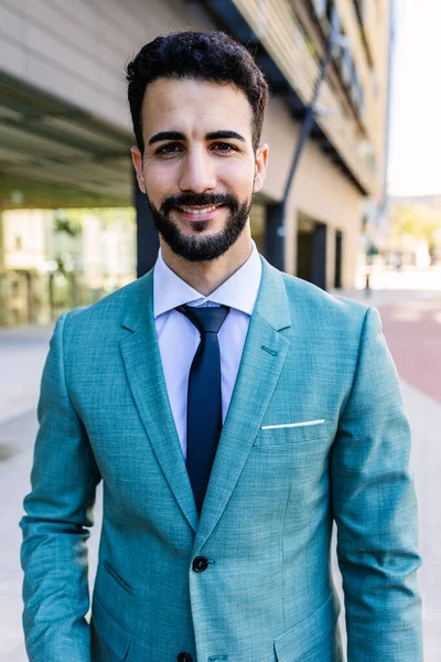 Vertical portrait of young successful businessman smile at camera standing outside office. Handsome professional corporate male head shot. Business and people concept.