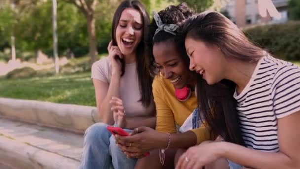 Троє Молодих Багаторасових Друзів Розважаються Використовуючи Мобільний Телефон Сидячи Відкритому — стокове відео