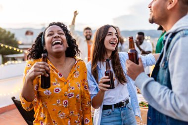 Çatıdaki partide dans eden bir grup genç. Çeşitli arkadaşlar ev terasında doğum günü kutlarken bira içerek eğleniyorlar..