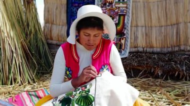 Genç Latin Amerikalı Perulu kadın Uros, Titicaca Gölü, Puno 'da renkli kumaş dokuyor. Aymara yerlileri. El yapımı geleneksel.