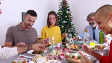 Mutlu çoklu jenerasyon aileleri evde Noel yemeğinin tadını çıkarıyor. Geniş bir grup insan birlikte eğleniyor. Xmas 'ın yemek masasının etrafında buluşmasını kutluyorlar..