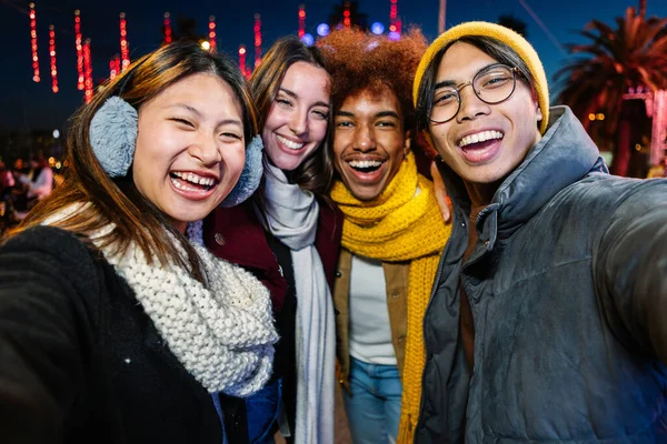 Happy young group of diverse people having fun taking selfie together on winter