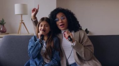 Genç Latin kadın anne kızıyla karaoke yapıyor. Bekar bir aile evde birlikte eğleniyor..