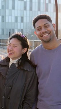 Birbirlerine sarılmış, gülümseyen ve dışarıda eğlenen bir grup genç arkadaş. Birleşik neşeli bin yıllık öğrenci topluluğu şehir caddesinde bir arada duruyor. Dikey 9: 16 ekran görüntüsü.