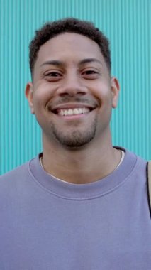 Aquamarine binasının arka planında kameraya gülümseyen mutlu Latin öğrenci. Dikey ekran 9: 16 görüntü görüntüsü.