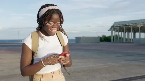Ευτυχισμένη Χιλιετή Μαύρο Κορίτσι Που Διασκεδάζει Κουβεντιάζοντας Συσκευή Smartphone Ενώ — Αρχείο Βίντεο