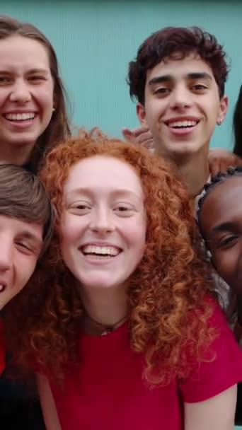 青い背景の上に一緒に立っている十代の学生の友人の多様なグループ カメラで笑顔で楽しんでいる若い多人種大学の人々の肖像画 16スクリーン ビデオ — ストック動画