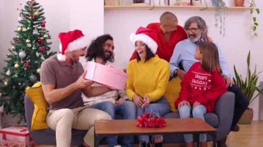 Mutlu bir aile Noel 'i birlikte kutluyor. Noel Baba şapkalı güzel bir kadın Noel arifesinde evde açılış hediyesi veriyor..
