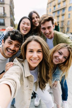 Genç milenyum insanlarının şehir caddesinde telefonla selfie çekerken dikey çekimleri. Gençlik toplumu ve arkadaşlık kavramı.