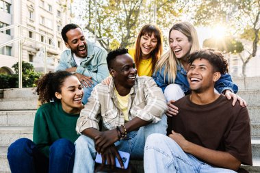 Genç bir grup öğrenci dışarıda birlikte rahatlarken eğleniyor. Millennial kolej öğrencileri birlikte şehir merdivenlerinde oturup konuşmanın tadını çıkarıyorlar. Dijital detoks ve gençlik toplumu kavramı.