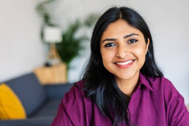 Closeup portrait of young indian woman smile at camera relaxing at home. Diversity and people concept clipart