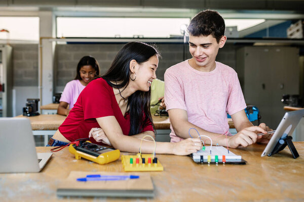 Young group of multiracial teenage students learning together electronic at high school. Diverse classmates studying at technology class. Education concept.