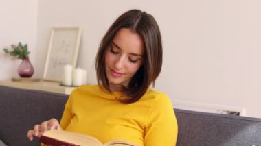 Evdeki kanepede otururken kitap okuyan güzel yetişkin bir kadının portresini yakından çek. Dişli gülümseme, güzel insanlar..