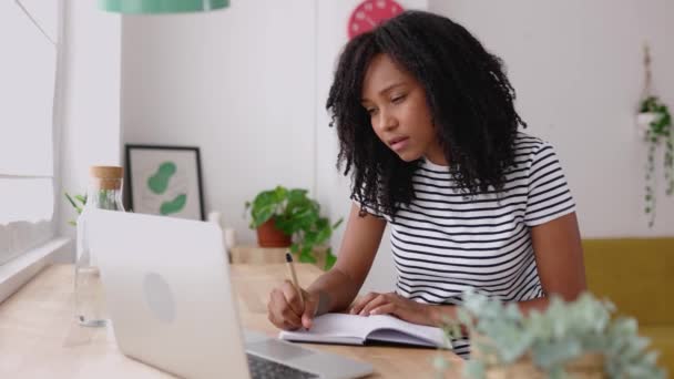 年轻的巴西女学生在家里用笔记本电脑记笔记 千年虫卷曲的女性在线学习听虚拟视频呼叫 商业和教育概念 — 图库视频影像