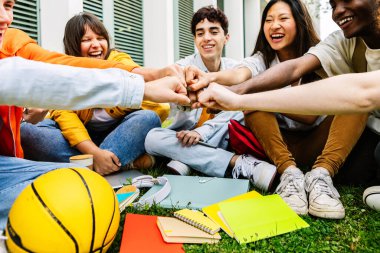 Bir grup üniversite öğrencisi destek ve işbirliği göstererek el ele tutuşuyor. Birbirlerini destekleyen ve motive eden sınıf arkadaşlarının gençlik cemiyeti