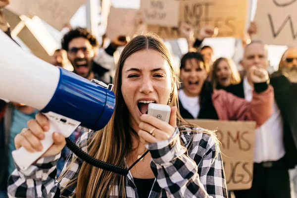 stock image Large group of diverse people manifesting against war or attack on a country. Female activist using megaphone outdoors. Stop war signs and banners in a peace demonstration