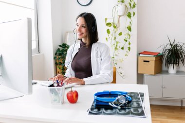 Hastane danışma odasında çalışan mutlu kadın doktor. Sağlık ve teletıp konsepti.
