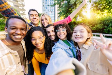 Çeşitli mutlu öğrenci arkadaşlardan oluşan genç bir topluluk birlikte selfie portresi çekiyorlar. Milenyum insanları açık havada eğlenerek eğleniyor. Gençlik, çeşitlilik ve arkadaşlık kavramı.