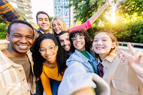 Young community of diverse happy student friends taking selfie portrait together. Millennial group of people having fun enjoying free time outdoors. Youth, diversity and friendship concept.