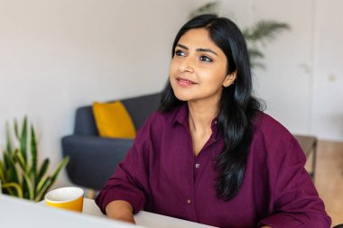 Evde dizüstü bilgisayarla çalışan düşünceli genç Hintli kadın. İş ve teknoloji kavramı.